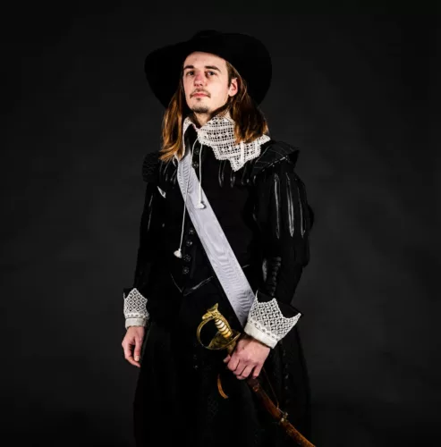 Man in een zwart historisch kostuum met een hoed en een zwaard in zijn hand.