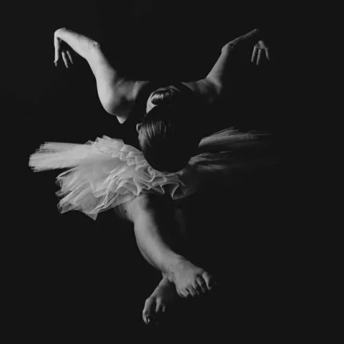 Zwart-wit afbeelding van een balletdanseres in een tutu met een gebogen houding.