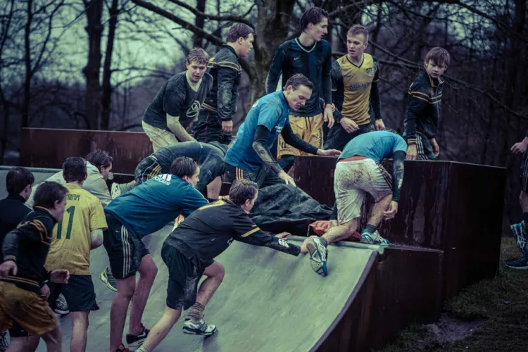 Jongeren in sportkleding die samenwerken op een hellend oppervlak tijdens een teambuilding activiteit.