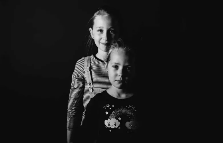 Twee meisjes in zwart-wit, één met een gestreepte trui en de ander met een zwart shirt met een ontwerp.