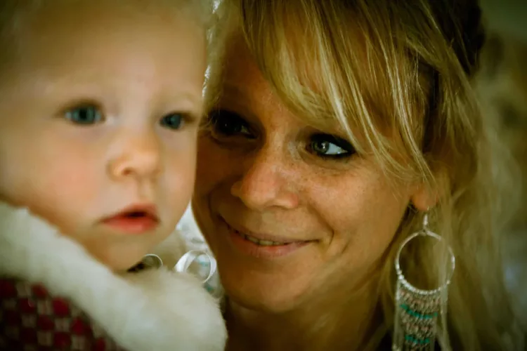 Een vrouw met een glimlach kijkt naar een kind dat dichtbij haar is.