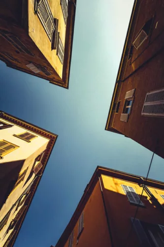 Uitzicht naar de lucht tussen vier gebouwen met gele gevels in Modena, Italië.