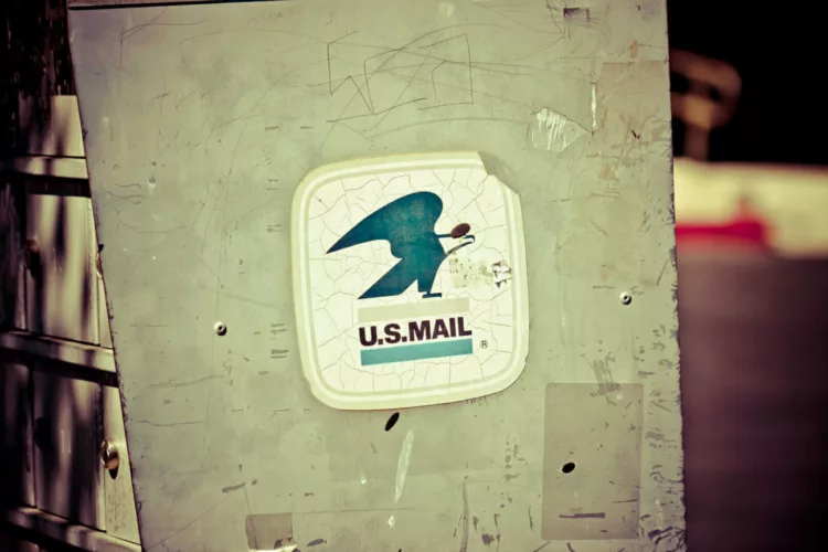 U.S. Mail sign featuring a blue bird logo on a weathered background.