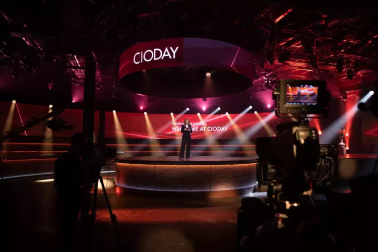 Een podium met een spreker tijdens het CIODay evenement in een studio met verlichting.