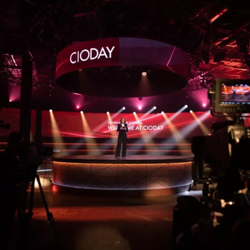 Een podium met een spreker tijdens het CIODay evenement in een studio met verlichting.