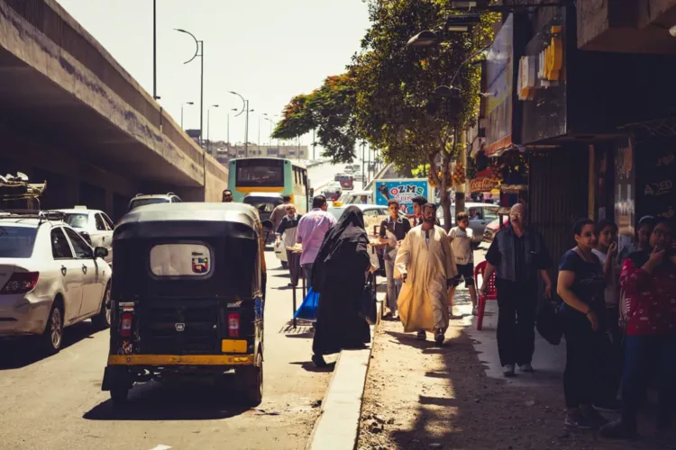 Drukke straat in Cairo met verschillende voertuigen en voetgangers op de stoep.