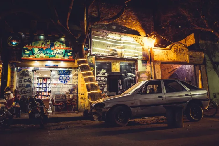 Witte auto geparkeerd voor een winkel met verlichting in Cairo, Egypte, 's nachts.