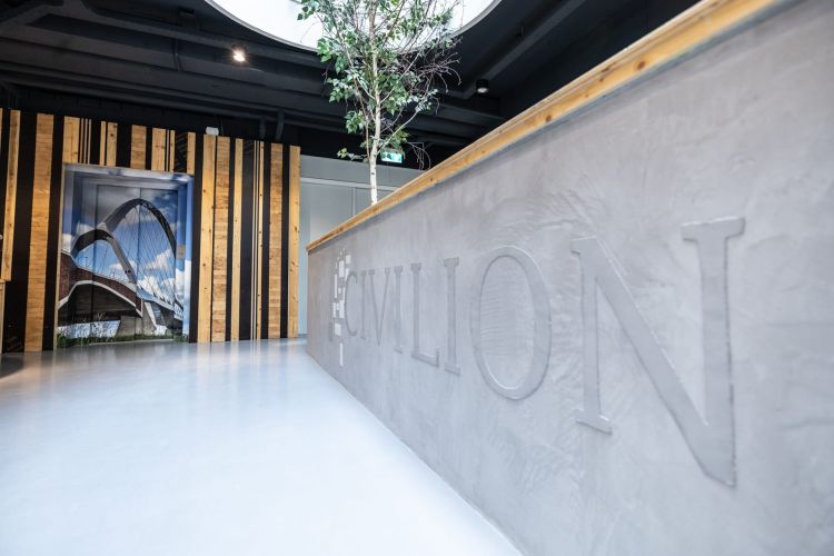 Interieur van Civillion met een betonnen balie en een boom in de ruimte.