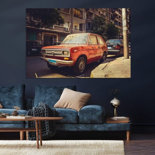Oude oranje auto geparkeerd op een straat met andere voertuigen op de achtergrond.
